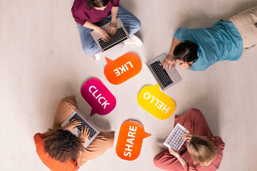 “Group of people on laptops surrounded by social media icons, representing Clear to Launch Dental Marketing’s guide to creating engaging dental social media content