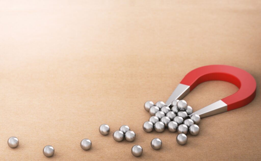 Red horseshoe magnet attracting metal balls, symbolizing dental patient retention strategies and how dental practices can attract and keep loyal patients.