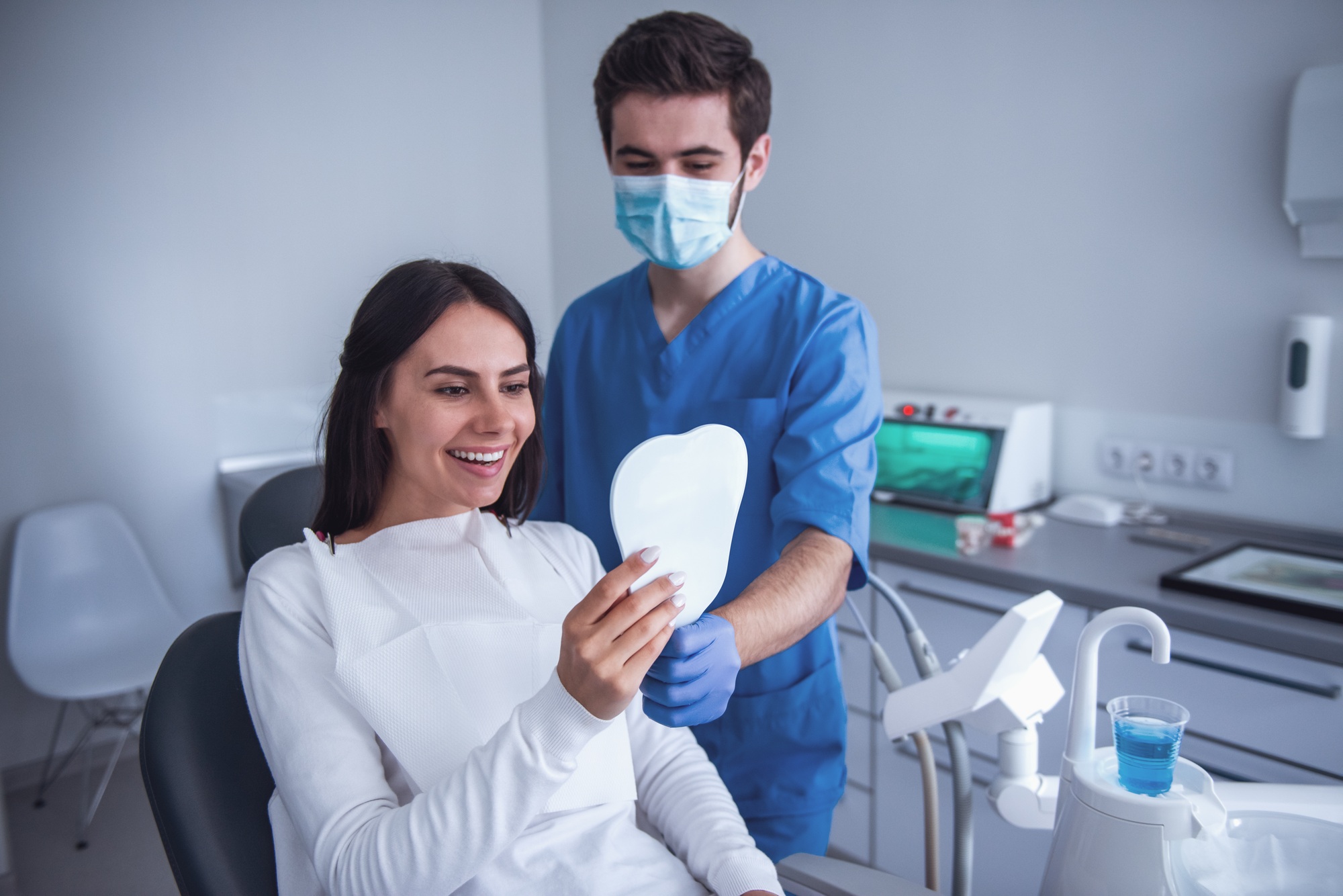 Happy dental patient looking in mirror after treatment, representing improved patient experience and conversion from an optimized dental website.
