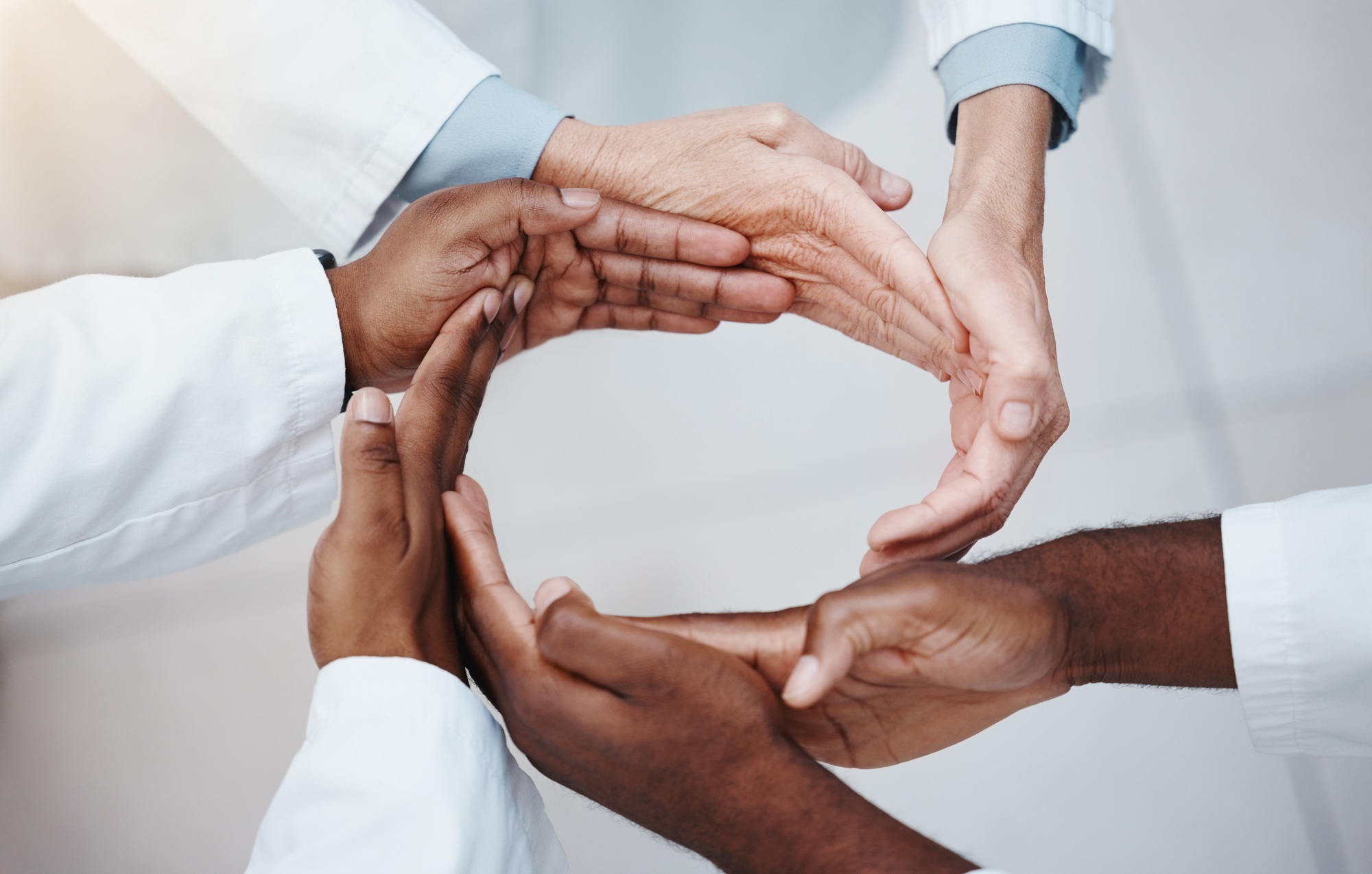 Diverse hands forming a circle symbolizing unity and trust, representing Clear to Launch Dental Marketing’s focus on building patient trust through testimonials and reviews